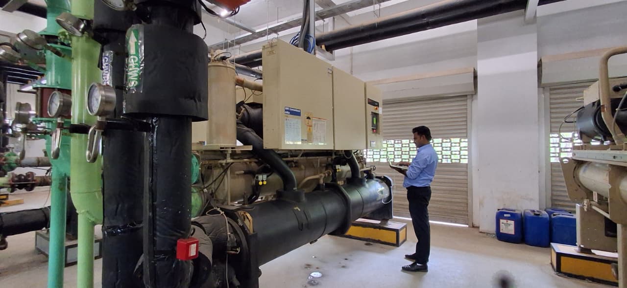 GS Aircon engineer recording readings during an inspection round in a water-cooled chiller plant room