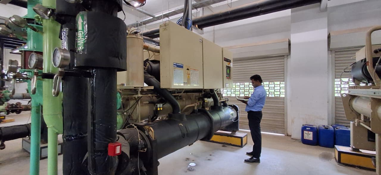 Engineer logging operating parameters at a water-cooled screw chiller control panel